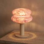 Lampe sans fil Berceuse rose allumée sur une console en travertin