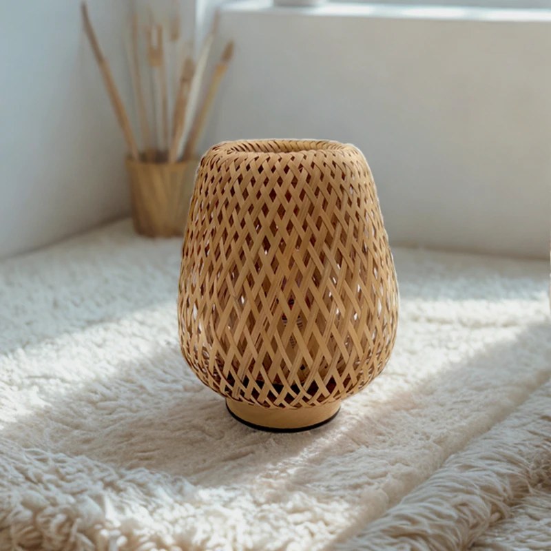 Petite lampe en bambou tressé Bourrée sur un tapis blanc