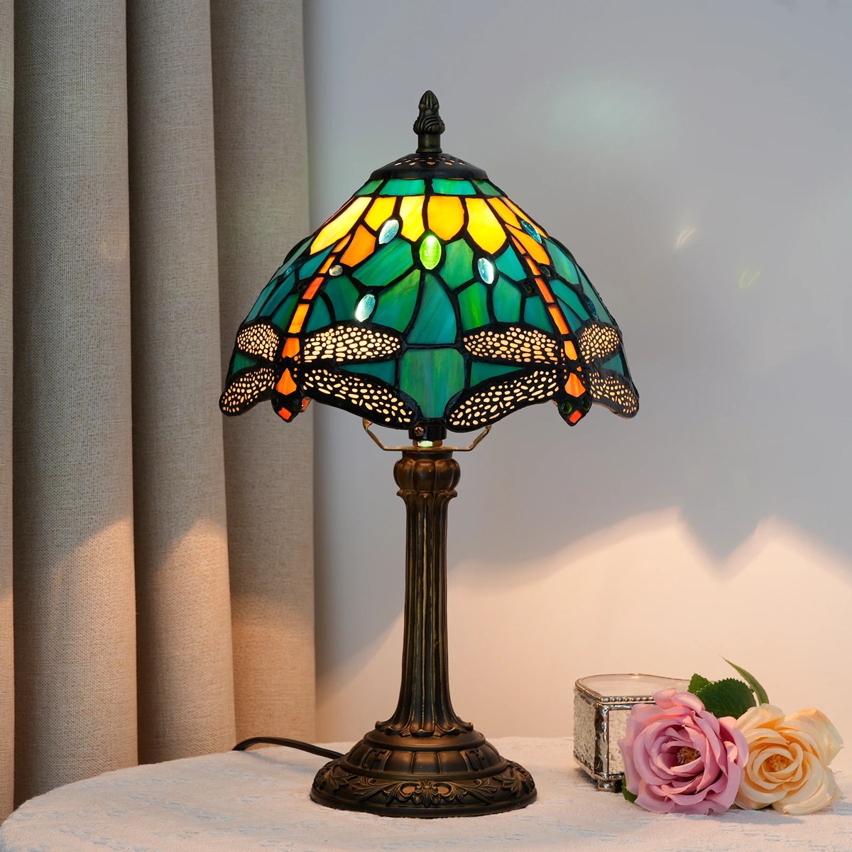 Lampe Tiffany Gavotte allumée, libellules en verre teinté vert et ambre