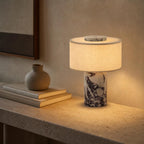 Lampe sans fil Adagio en marbre violet allumée sur une console en travertin