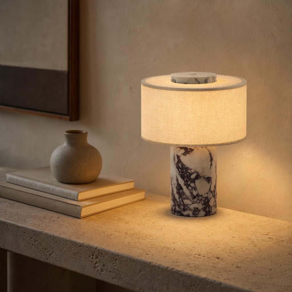 Lampe sans fil Adagio en marbre violet allumée sur une console en travertin