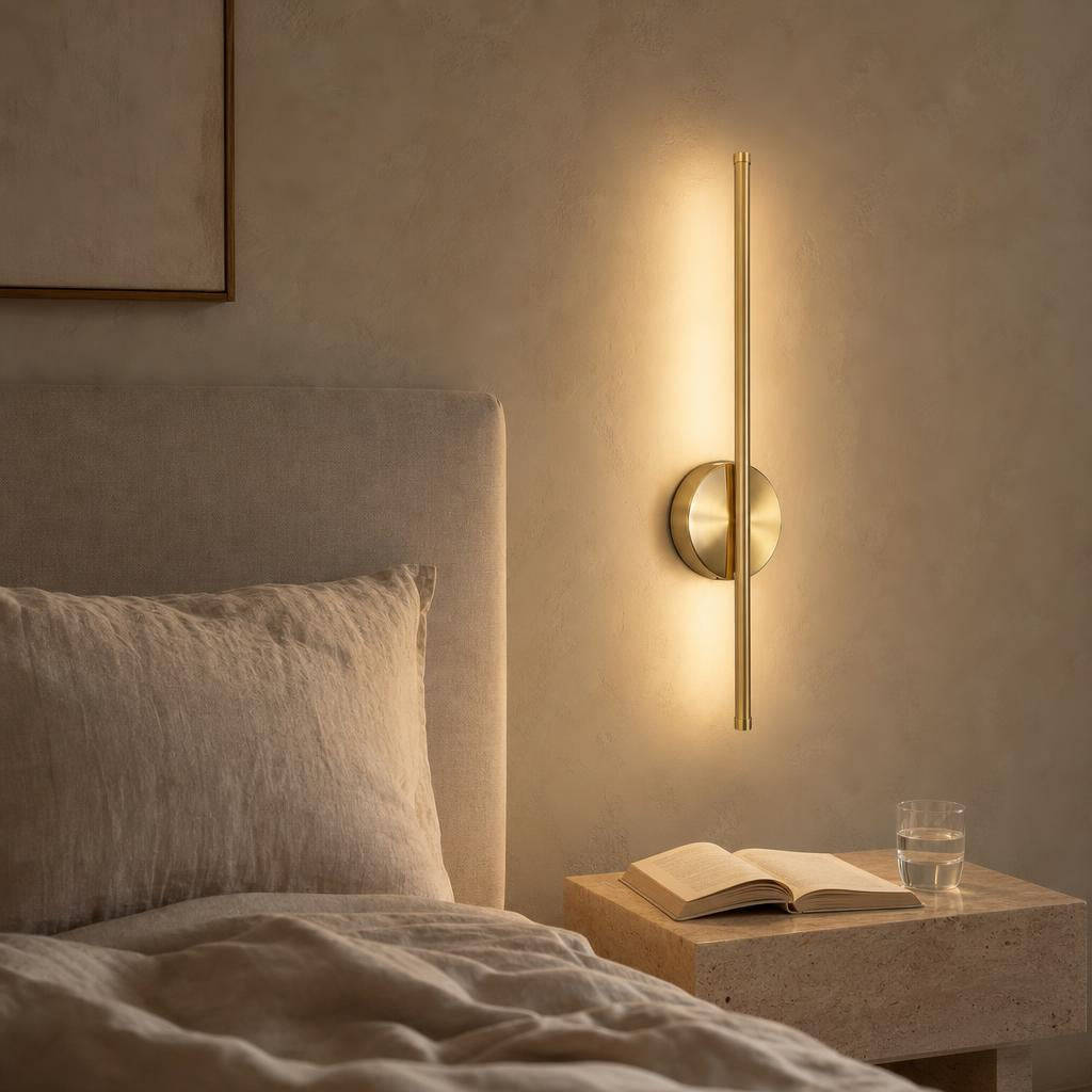 Applique sans fil Toccata dorée allumée à côté d'un lit en lin