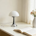Lampe champignon Polka blanc opalin, pied chromé, sur une table de chevet
