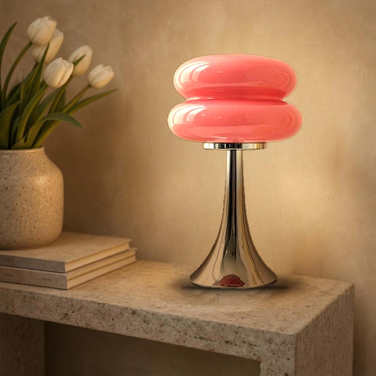 Lampe macaron Swing en verre rose allumée sur une console en pierre, pied tulipe chromé