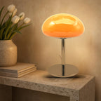 Lampe nuage Mazurka en verre opalin orange allumée sur une console en pierre