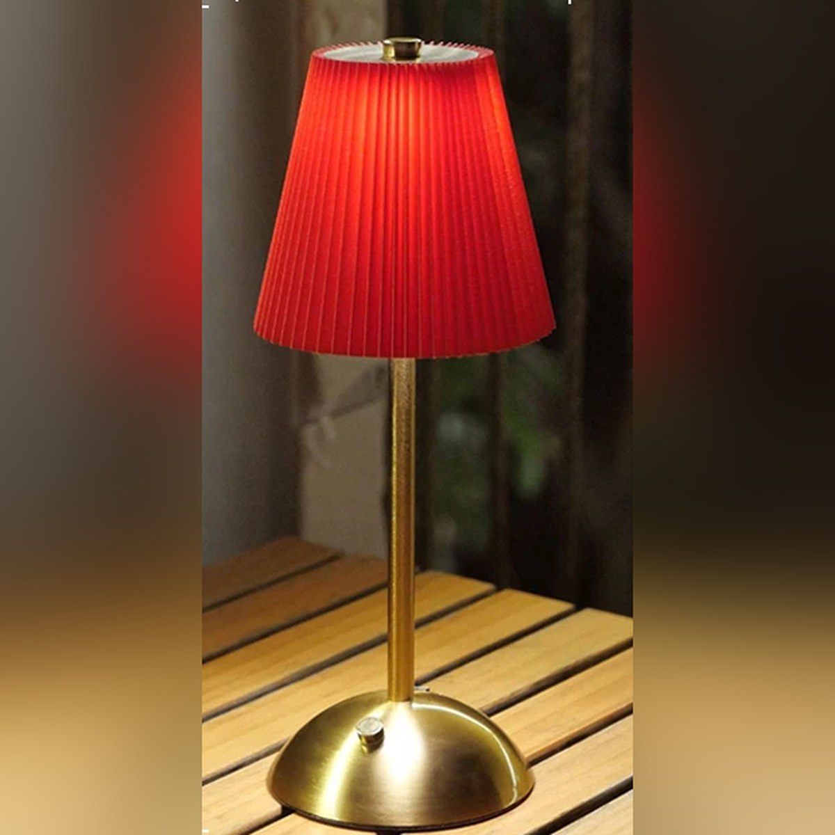Lampe sans fil Musette à abat-jour plissé rouge sur une table en bois
