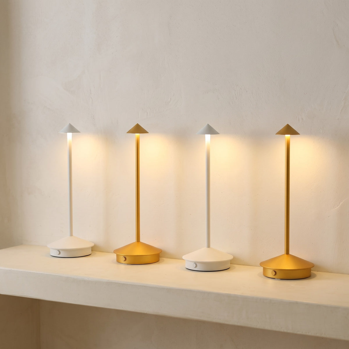 Quatre lampes sans fil Solo blanches et dorées allumées sur une étagère