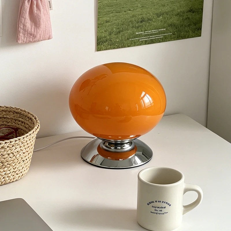 Lampe globe Opus orange en verre opalin sur socle chromé, sur un bureau