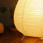 Détail du papier de riz plissé et des pieds en métal de la lampe Pavane