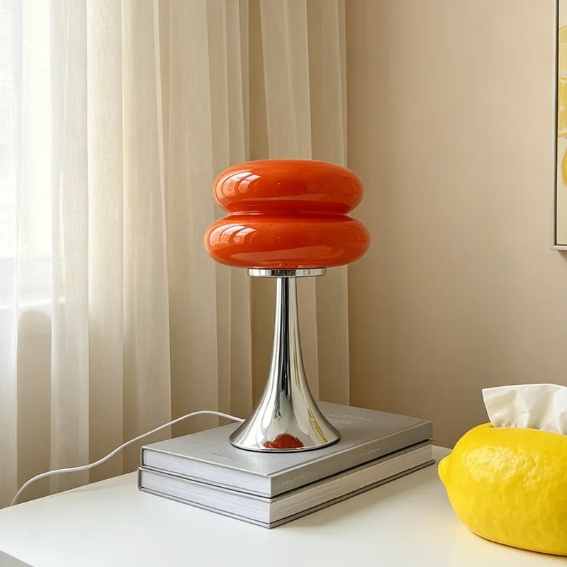 Lampe Swing orange posée sur des livres, près d'une fenêtre